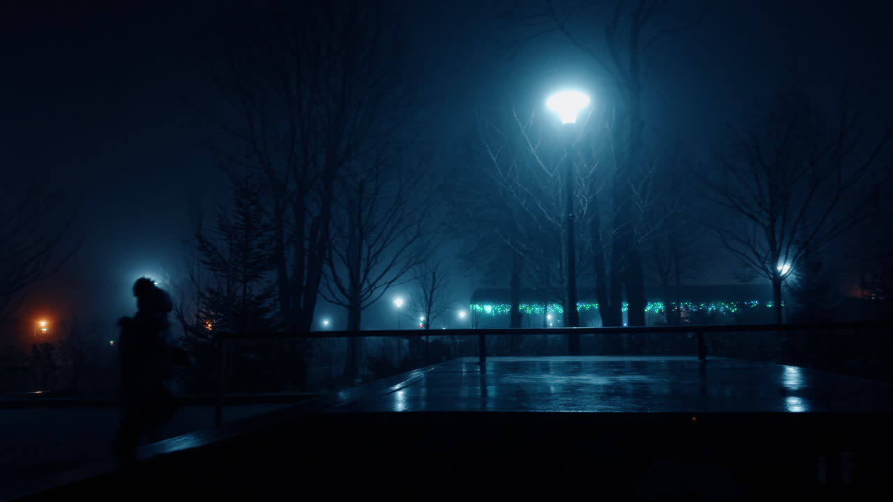 Little baby wearing warm clothes and cap running outdoors at night. City street lamps and garlands are lit at backdrop.