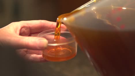 Pouring-CBD-and-beeswax-infused-ointment-into-small-container