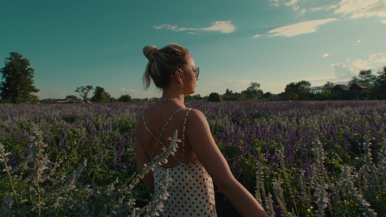 Giovane donna che cammina attraverso un campo di lavanda in fiore al tramonto.