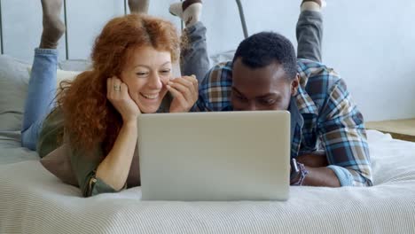 pareja relajándose en la cama y viendo la computadora portátil