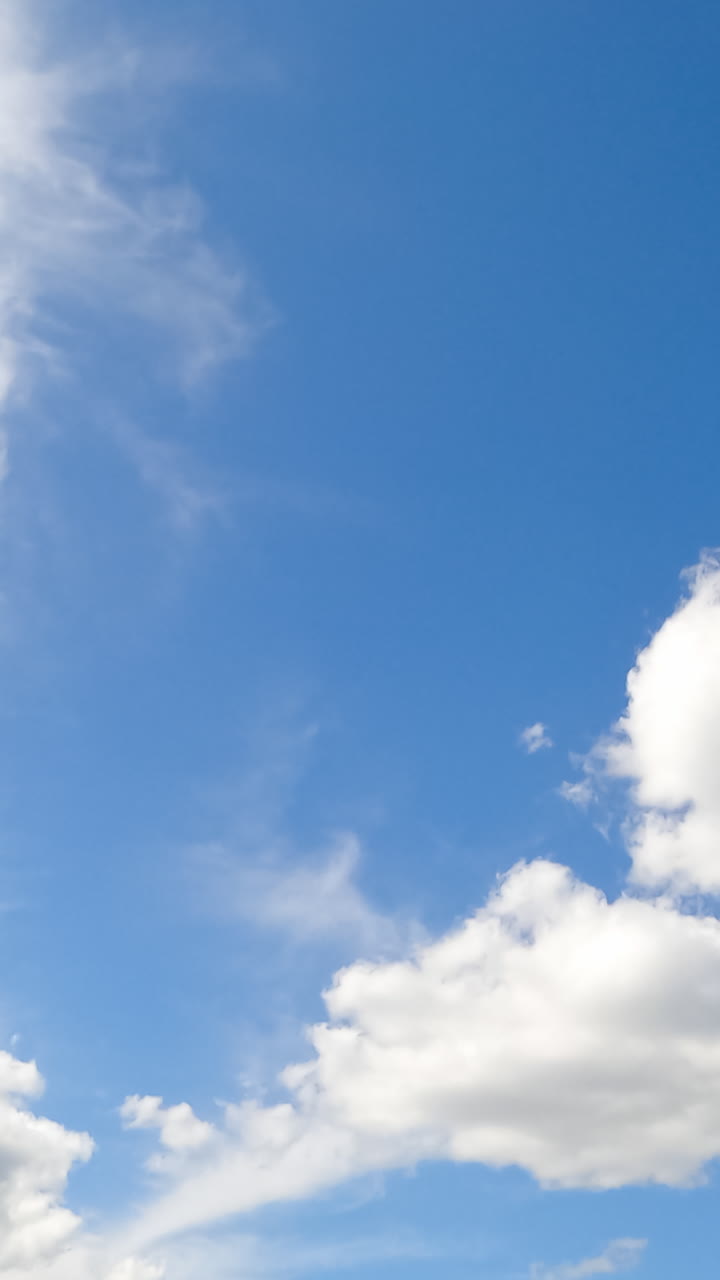Sunny day clear skies covered with white clouds lit with bright sun. Beautiful soft cloudscape low angle view. Timelapse. Vertical video