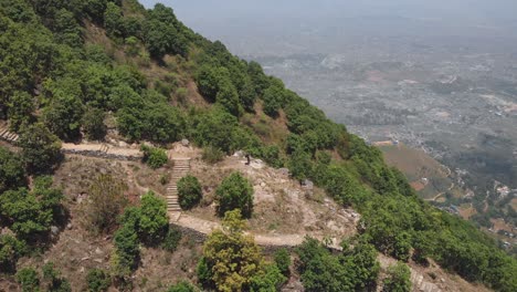 aerial circular shot from a drone of an young man enjoying the view of kathmandu from a hiking trail, nepal