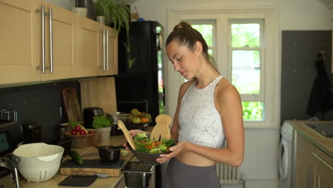 mujer joven que parece orgullosa de la ensalada recién hecha