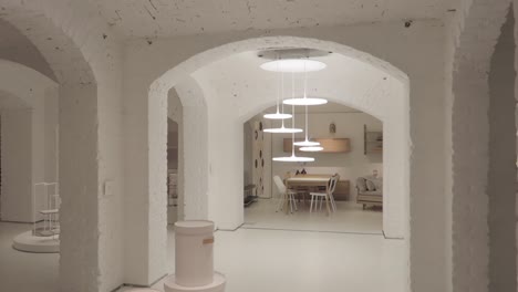 Sótano-De-Diseño-Blanco-Con-Decoración-Y-Arcos-Minimalistas,-Tiro-Moviéndose-Desde-Detrás-De-Un-Pilar-A-La-Habitación-Y-Enfocando