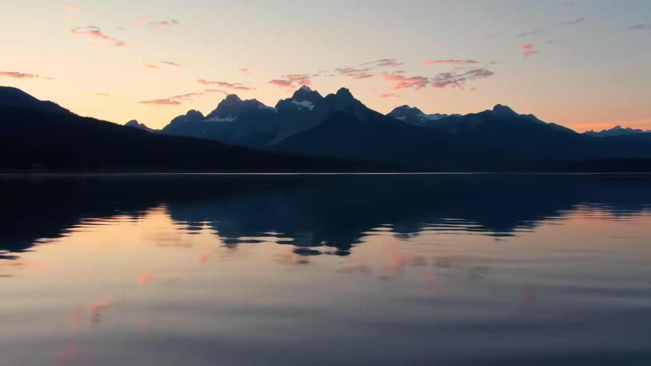 Vibrant sunset colors illuminate the sky above Grand Teton National Park, creating stunning reflections on the calm lake. A perfect moment showcasing nature's beauty and tranquility.