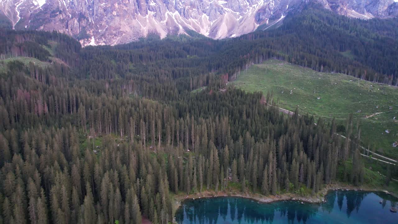 Veduta aerea panoramica del lago alpino di Carezza circondato da una foresta di conifere