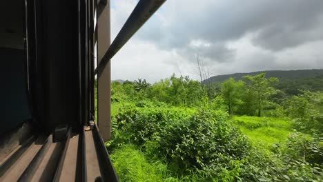 black clouds and greenery forest view from train window in konkan railway