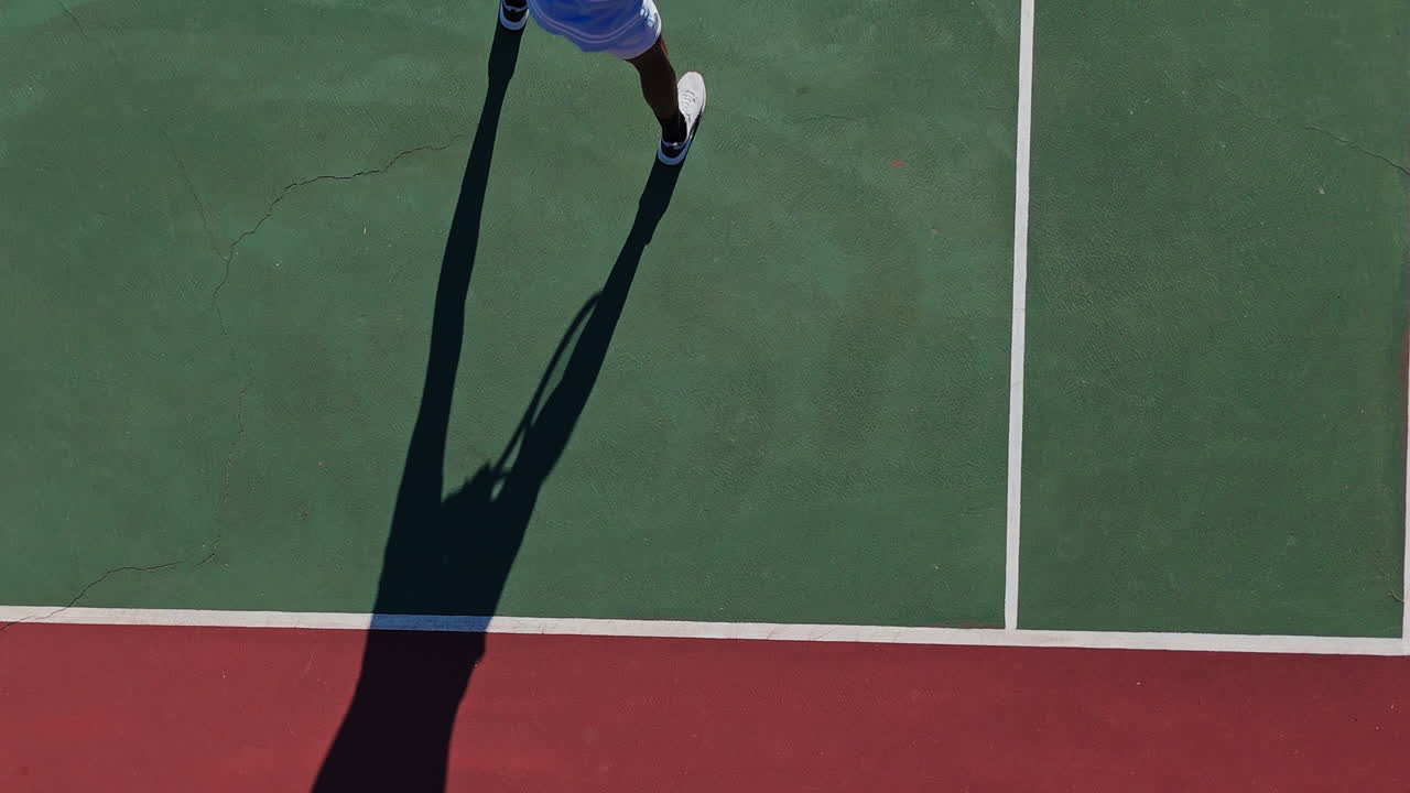 Overhead view of tennis player serving on a red and green court