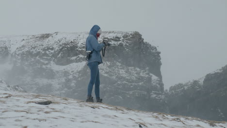 mujer tomando fotografías en el espectacular paisaje invernal de las islas feroe