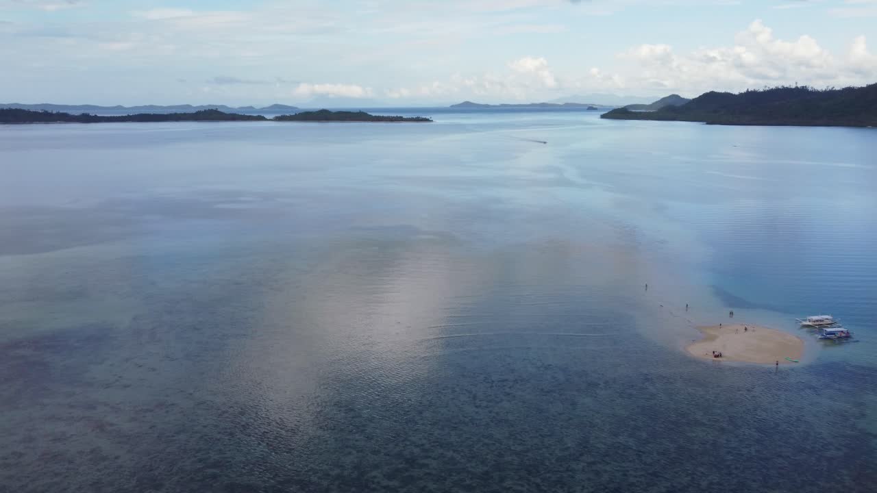 드론이 작은 섬을 가로질러 파닝하여 관광 보트와 스타피시 샌드크, 포트 바튼의 사람들을 드러니다.