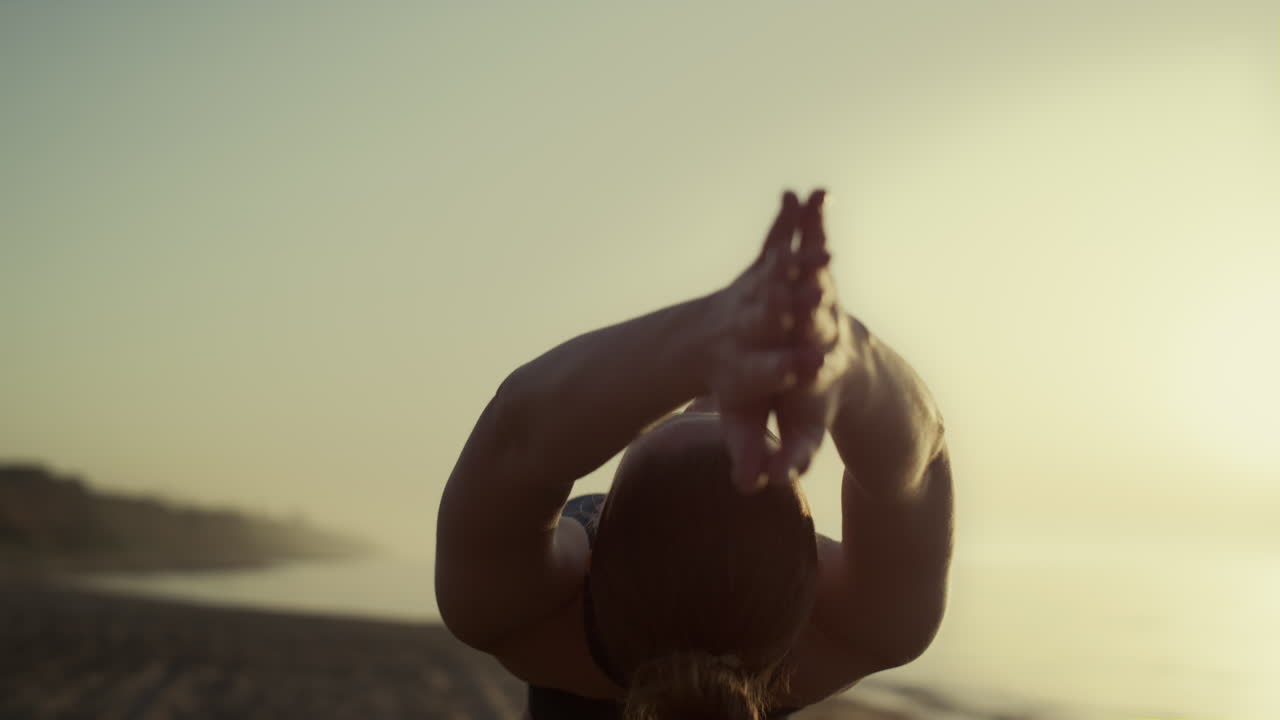 chica deportiva levanta las manos inclinando el cuerpo hacia atrás al atardecer. mujer practicando yoga.