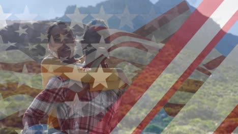 Animation-of-american-flag-over-smiling-diverse-couple-embracing-in-mountains