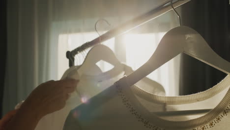 A-woman-chooses-clothes-in-the-dressing-room.-Silhouette-in-the-sun,-side-view