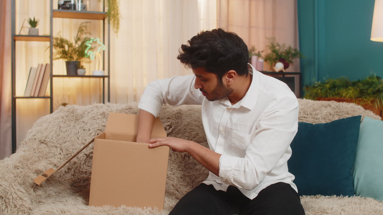 Indian man shocked checking delivery package discovering broken wireless headphones disappointed