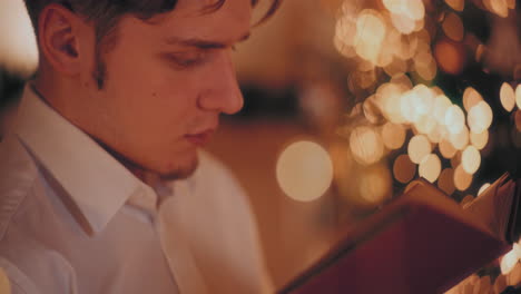 man reading book in illuminated home during christmas