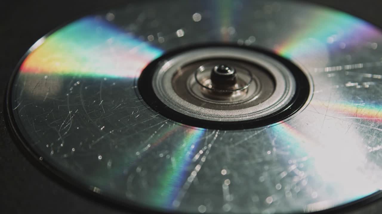 Spindel aktiveres, roterende optisk disk viser regnbuer, ridser og støv på mørk bakke med nav