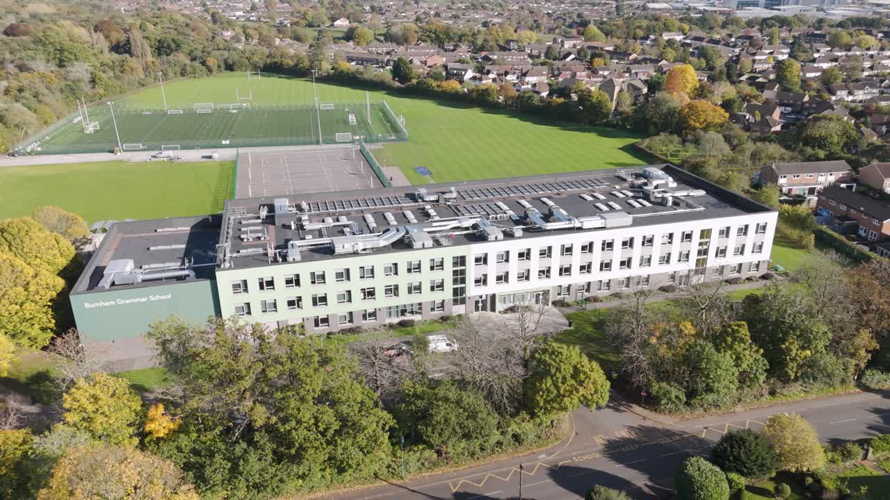 Orbital aerial view of Burnham Grammar School, with expansive green sports fields in the backdrop, Berkshire UK, October 2024