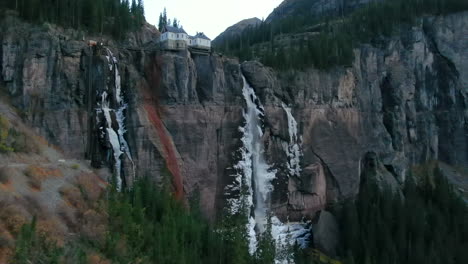 bridal veil falls telluride colorado aerial drone frozen ice waterfall autumn sunset cool shaded rocky mountains silverton ouray millon dollar highway historic town landscape slow right pan up reveal