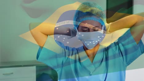 Animation-of-flag-of-brasil-waving-over-female-doctor-in-hospital
