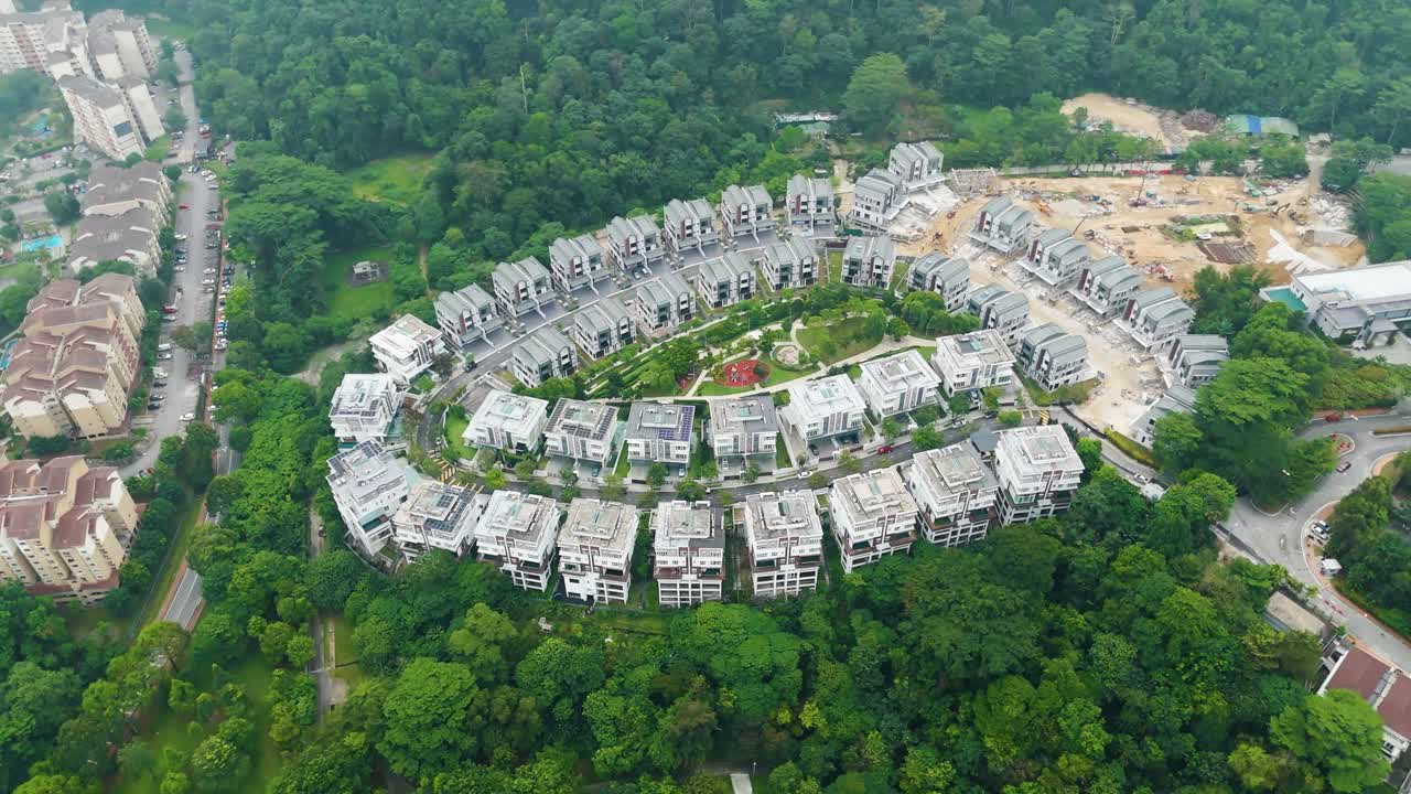 Orbiting drone shot of luxury housing development in Petaling Jaya, Kuala Lumpur, surrounded by greenery and ongoing construction in a forested suburban area. Malaysia