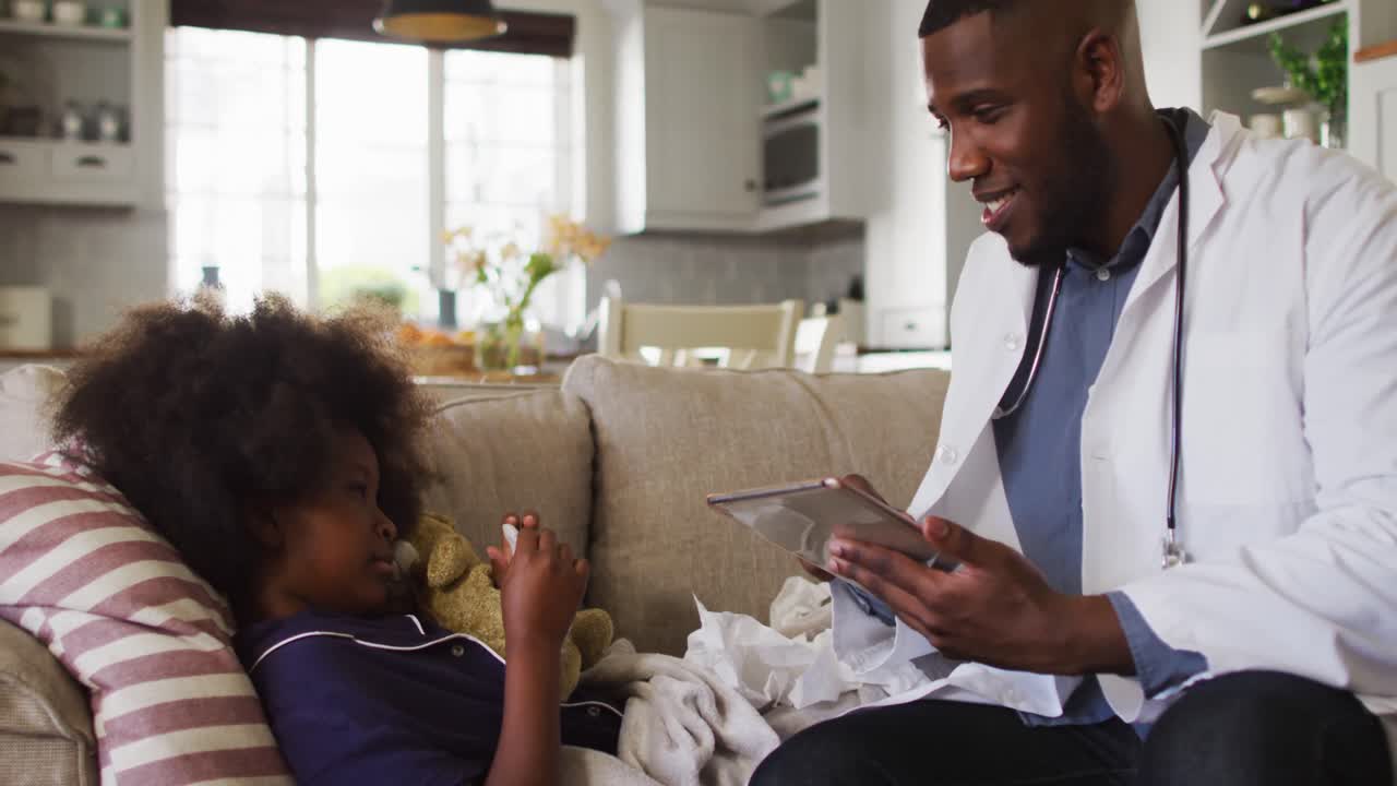 African american doctor using digital tablet and talking to sick girl at home