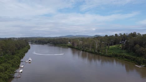 Volando-Sobre-Un-Río-Marrón-Donde-Un-Bote-Da-La-Vuelta-En-El-Río