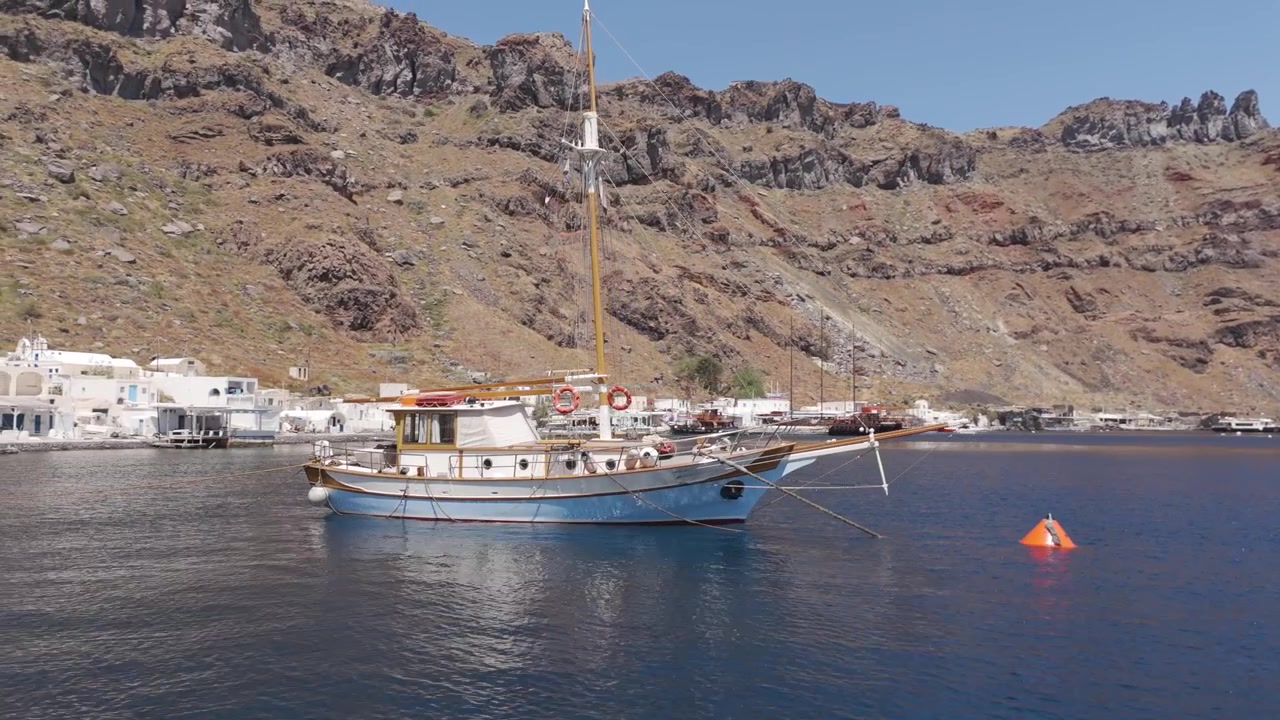 Barca a vela in legno ancorata nelle calme acque della caldera vicino a Thirasia, Santorini, Grecia