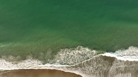 waves breaking at seaside aerial tracking right