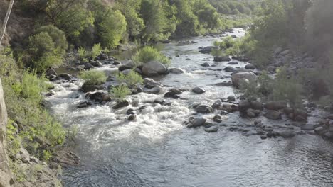a drone flies over an idyllic stream in a mountain set area.