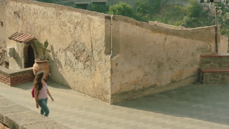 Tracking-shot-of-attractive-Italian-woman-walking-to-a-viewpoint-in-Italian-village-during-summer