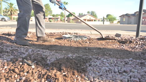 man shoveling heavy clay sand to dig out an underground trash can, slow motion