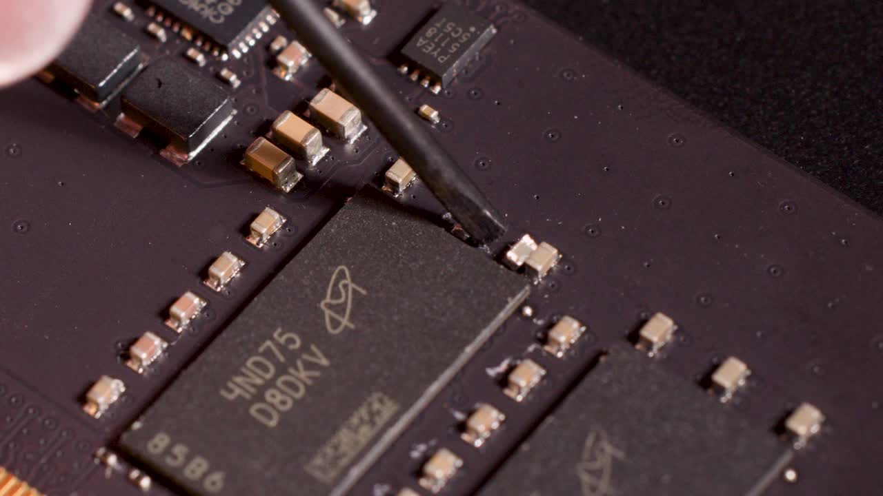 Close-up of hand tool indicating microchip on circuit board, soft lighting, shallow depth of field