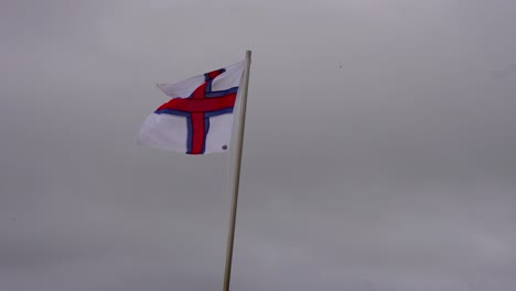 Cerca-De-La-Bandera-Feroesa-Arrastrada-Por-Fuertes-Ráfagas-De-Viento,-Clima-Tormentoso