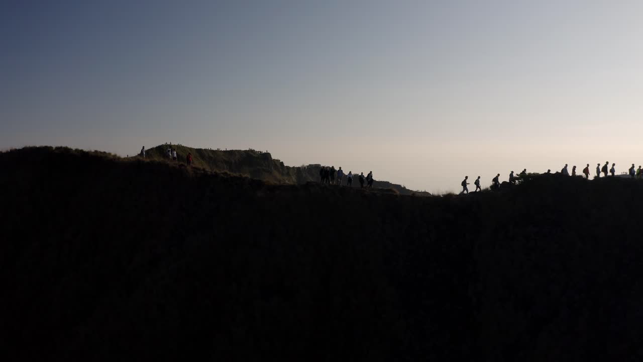 los excursionistas en la cumbre del volcán mout batur en bali, indonesia, caminan a lo largo de la cresta del cráter, la órbita aérea revela el disparo
