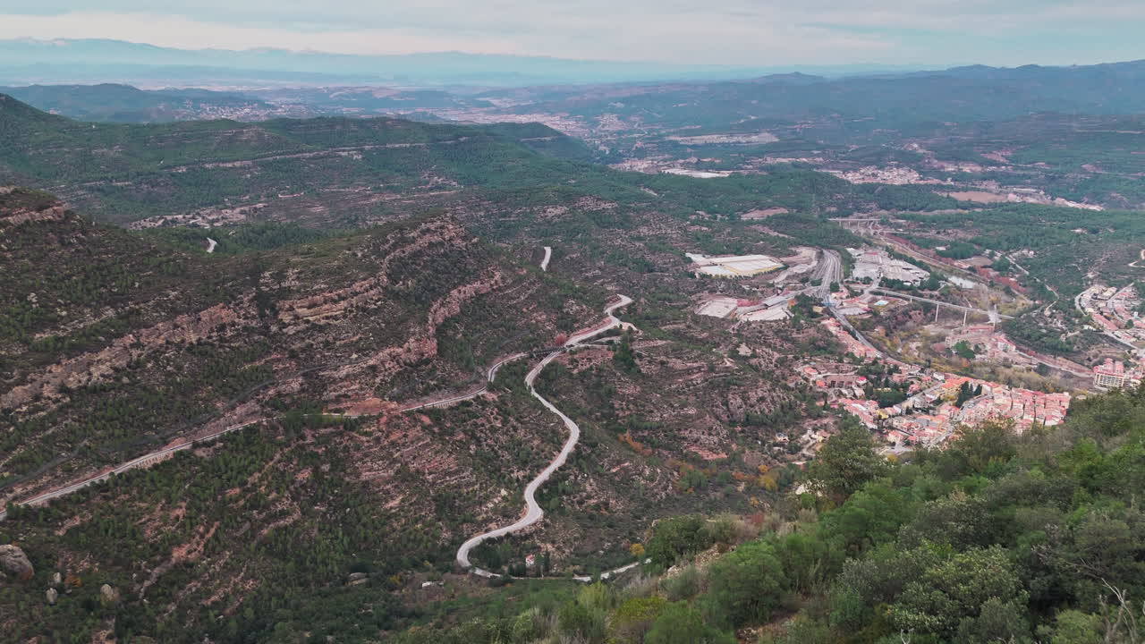 drone revela la toma, mostrando el pueblo ubicado debajo de la fuerza de las montañas, todo en el telón de fondo de un día nublado