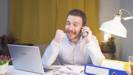 trabajador de oficina en casa que recibe buenas noticias por teléfono.