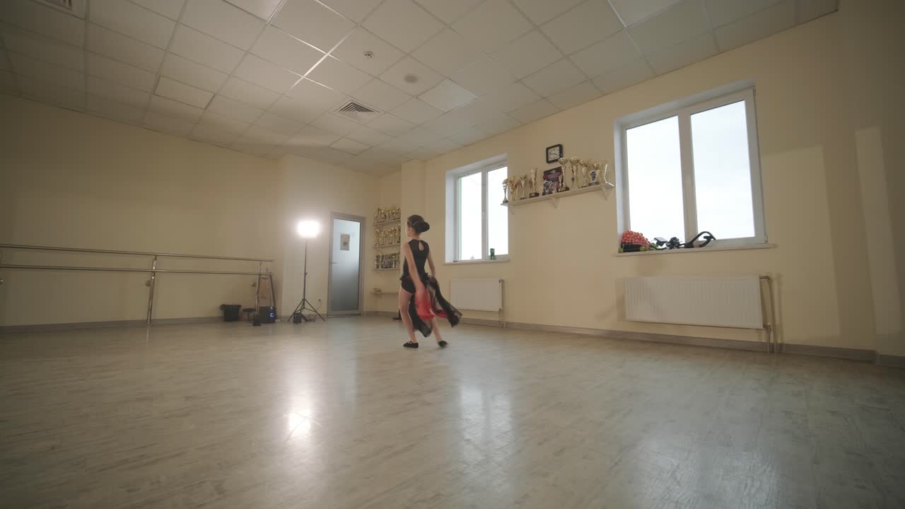 un grupo de jóvenes estudiantes de ballet con ropa de baile negra practicando posiciones en un amplio estudio de ballet con pisos de madera y barras montadas en la pared. expresiones enfocadas y movimientos sincronizados.