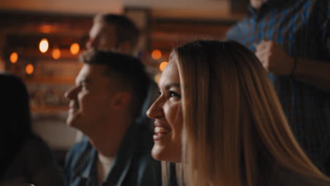 primer plano de un grupo de fanáticos de hombres y mujeres sentados juntos en un bar y viendo una transmisión en la televisión disfrutando de un gol marcado gritando y abrazándose. en el fútbol.