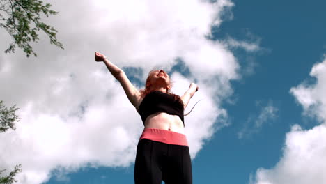 fit rothaarige jubeln unter blauem himmel