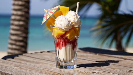 tropical mango strawberry ice cream parfait on a beach