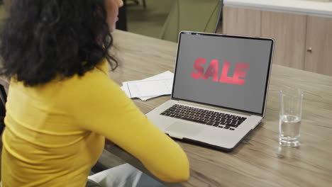 mujer biracial en la mesa usando portátil, compras en línea durante la venta, cámara lenta
