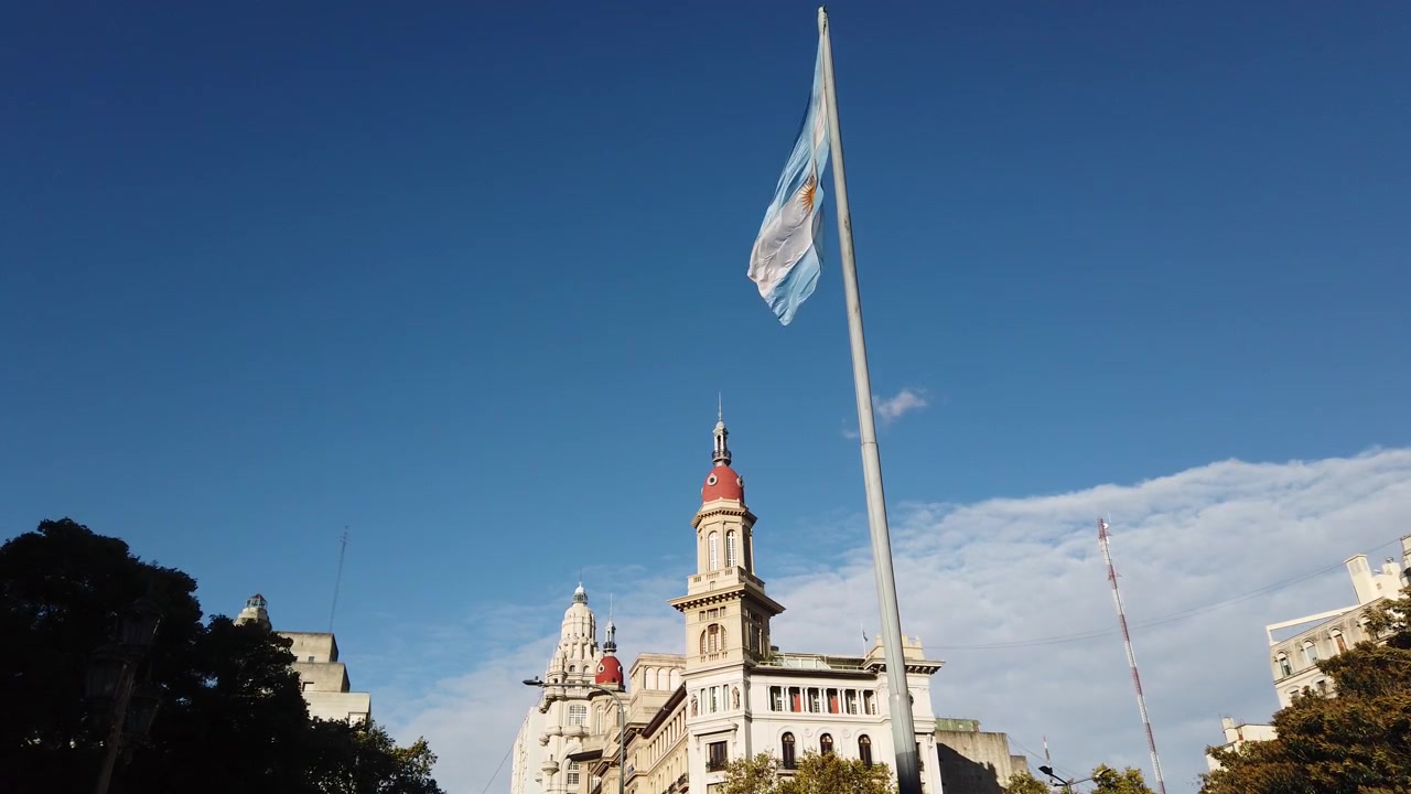 Bandeira Nacional Argentina tremulando sobre o histórico Palácio Barolo no horizonte de Buenos Aires