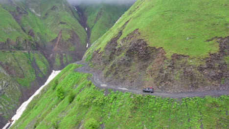 cinematic drone shot of a vehicle driving on the road to tusheti, one of the worlds most dangerous roads