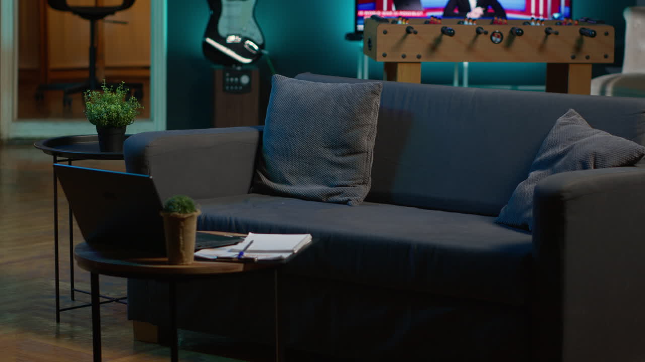 Stylish empty apartment loft with a comfortable couch and smart tv in the living room, modern space with decorations and funky neon lights. Studio with a coffee table and home theatre setup.