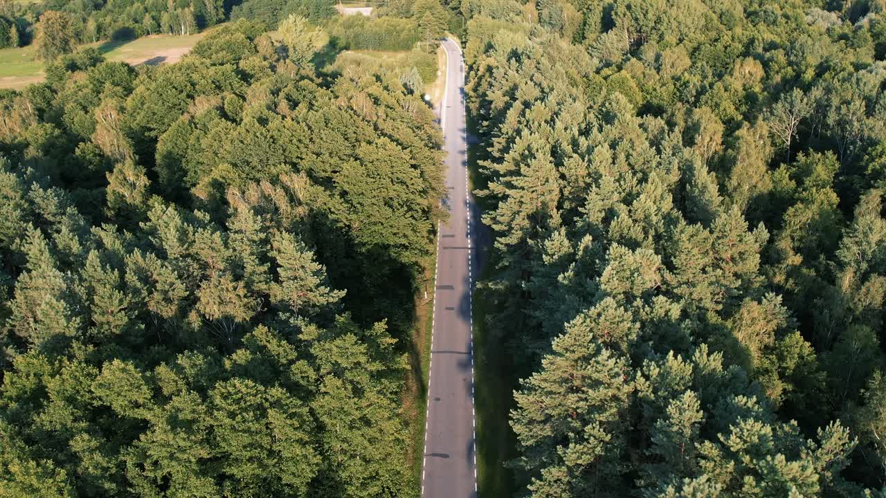 una foto aérea de una carretera vacía que atraviesa un bosque pacífico y verde durante el día