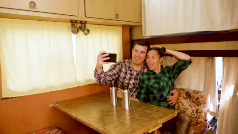 beautiful young couple making a selfie inside of their retro camper van