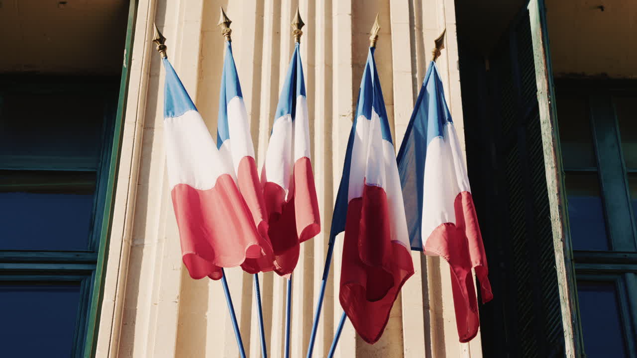 French national flags waving on the facade of a historic building in southern France