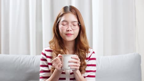 Asian-young-woman-on-a-cold-day-drinking-a-hot-cup-of-tea-to-relax