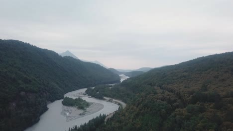 Aerial-view,-drone-flight-along-the-Glenn-Highway-and-the-Matanuska-River-in-the-Chugach-Mountain-Range-of-central-Alaska-on-a-cloudy-summer-day