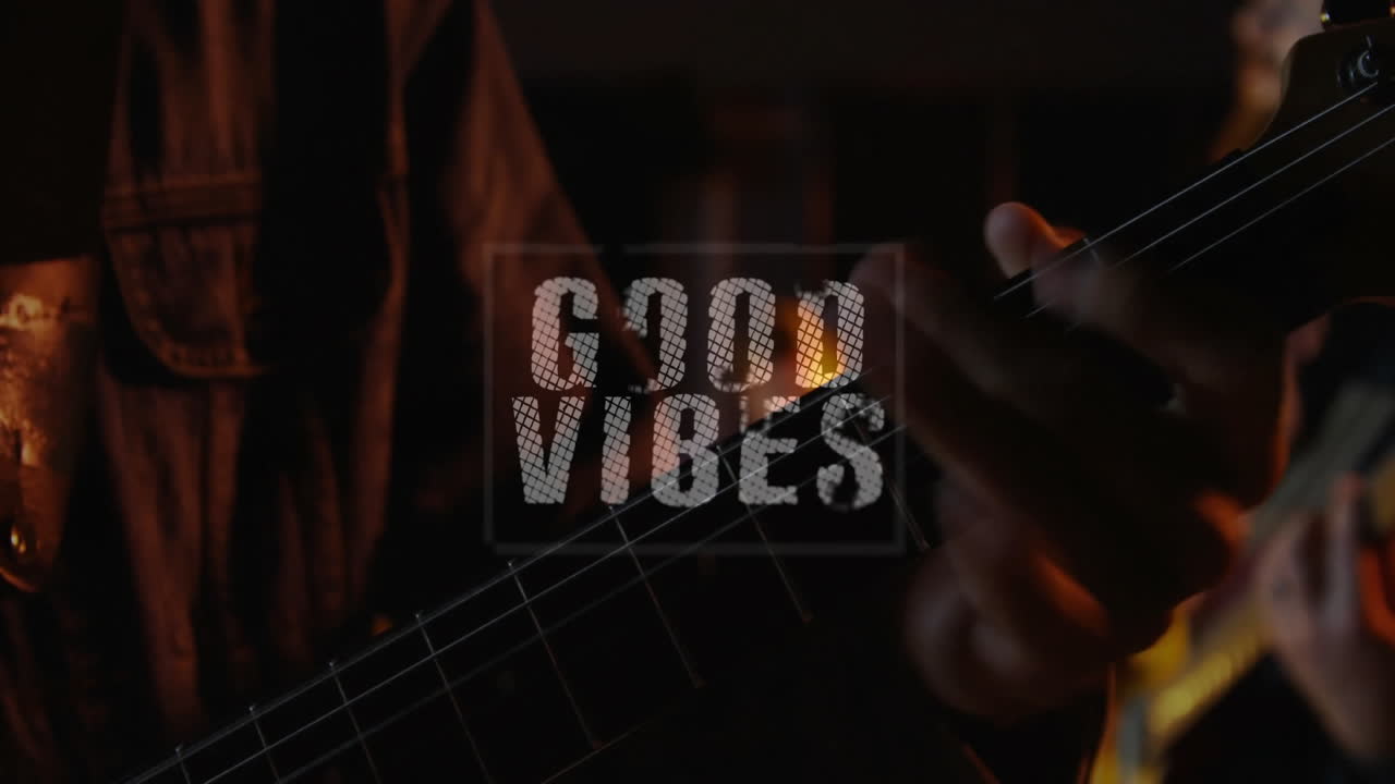 Guitarists hånd slår an på en akustisk guitar i et dæmpet musikstudie, viser animeret tekst "GOOD VIBES"